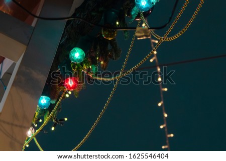 New Year decorations at the New Year's fair. Festive lights (garlands), balls and toys on buildings and trees. Christmas decorations. Closeup. Christmas and New Year celebration concept. Template. 