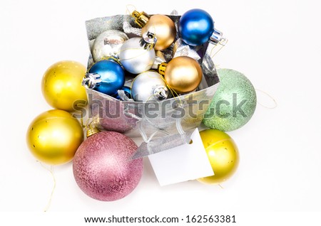 Gift bag filled with Christmas decorations and Christmas balls around