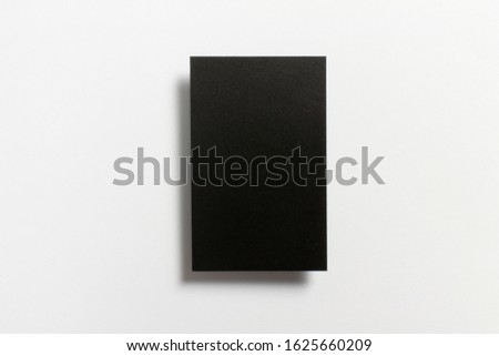 Black blank matt surface textured vertical business card flying and isolated on white background, UK standard size 85 mm wide x 55 mm high, real professional studio photo. 