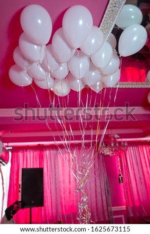 white balloons float on the white ceiling in the room for the party. Wedding or children birthday party decoration interior . Helium balloons red float.