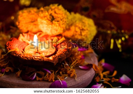 mid close up of beautiful glowing diya on rose petals with blurr
