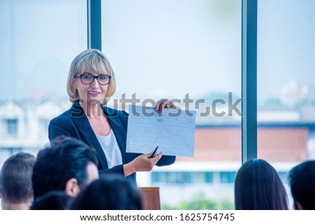 Female boss speaker  talk and show Document on corporate business conference. Unrecognizable people at conference hall. Business seminar and woman leader  concept