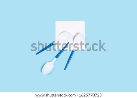 Pattern of white plastic spoons on blue background. Vertical picture. Flat lay, top view.