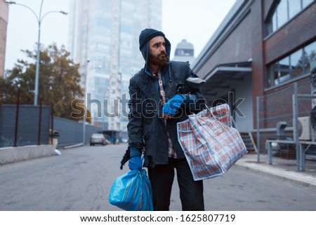 Bearded tramp man with bag on city street Royalty-Free Stock Photo #1625807719