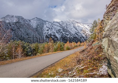 Landscape with mountains, forest, the first snow and road autumn