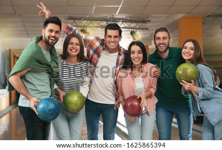 Group of friends with balls in bowling club