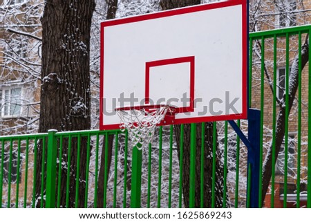 Basketball backboard on a city court with snow