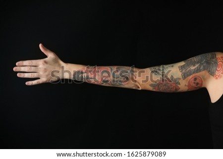 Woman with stylish tattoos on arm against black background, closeup