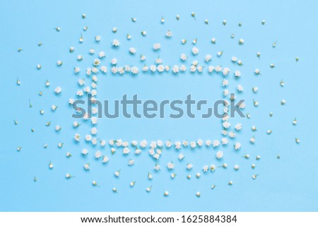 Rectangular frame made of small white flowers on a light blue background top view