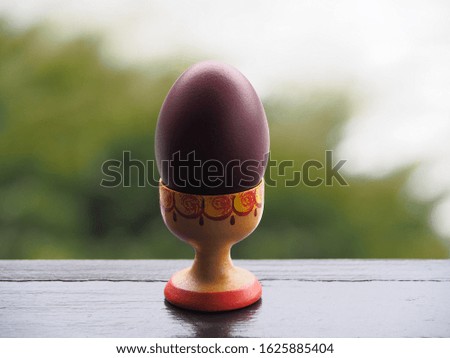 Isolated natural, painted Easter egg in a wooden stand in the garden closeup. Picture with a beautiful and useful chicken egg for the spring holiday Easter.
