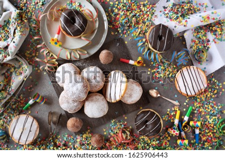 Sweet mardi gras donuts decorated on a gray table with colorful confetti and streamers. Flat lay Photography. 
Top view for a mardi gras background.