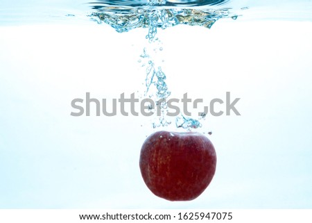 a fresh Apple falls into the water. Fruit in water. Water splashes, water splashes.