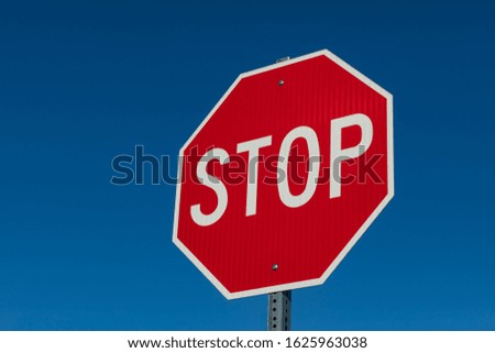 Closeup angled view of reflective stop sign isolated on deep blue sky background
