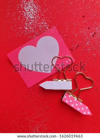 The flat lay and top of the clips in the shape of the heart on the red background with  glitter and the copy space. Valentine's day concept, love, romantic.