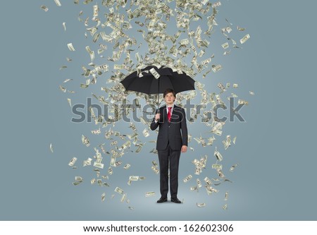 Businessman standing in the rain of dollars over grey background
