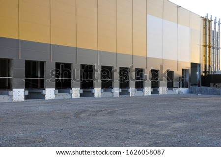 Outdoor photo of the construction of a large industrial and commercial building from technological metal structures. Logistic warehouse complex