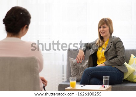 Two woman having a casual conversation sitting on a couch in the living room at home 