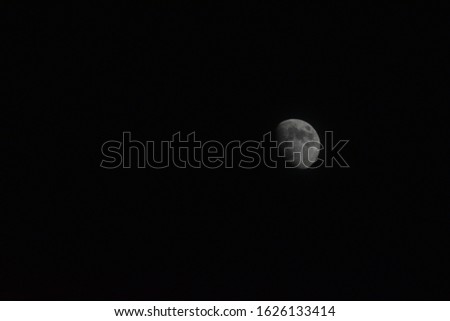 Picture of a mostly full moon, at night surrounded by darkness.