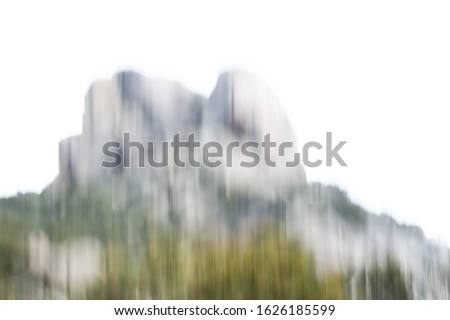 Artistic high-key painterly motion blur of granite tor rising above forested slopes