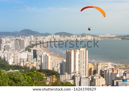 Aerial view of the beach in the city of Santos, Brazil,  and in the background the city of Guaruja.On the right, a paraglider enjoying the view.