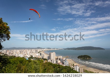 Aerial view of the beach in the city of Santos, Brazil,  and in the background the city of Guaruja.On the left, a paraglider enjoying the view.
