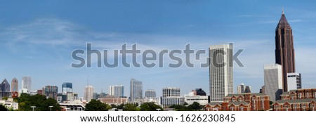 Downtown Atlanta Skyline showing several prominent buildings, apartments, offices and hotels under a blue sky.