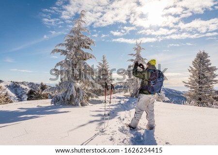 Hiker on top of the snowy mountain in the winter taking a picture with his cell phone outside of Boise, Idaho.