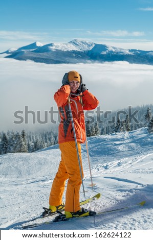 Young woman skier in orange suit standing on snow slope