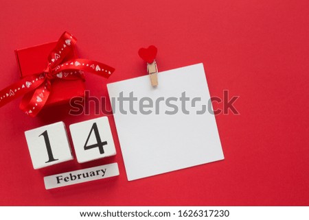 Happy Valentine’s Day top view card. 14 February wooden calendar and red romantic gift box on a red background