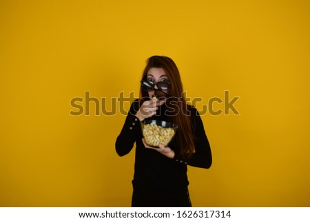 woman in 3d glasses eating popcorn on a yellow background