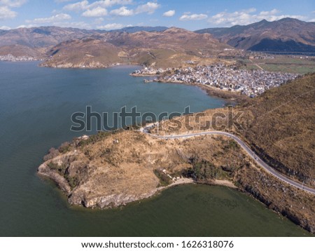 Aerial view of the Erhai Lake with a small hill and a Chinese village near the coast, shot with a drone in Dali, Yunnan Province, China in January.