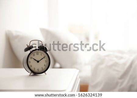 Black alarm clock on nightstand in morning. Space for text