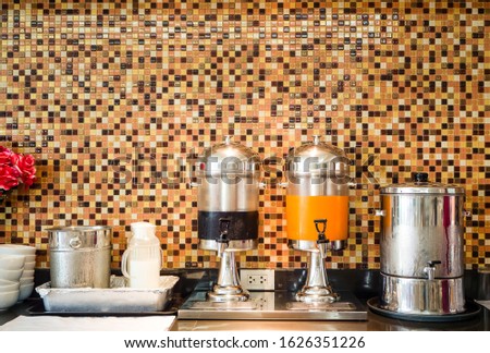 Fruit juice dispensers and coffee & tea water on a self service breakfast counter in a hotel.