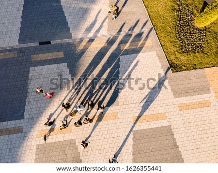 Photo of the shadows of people moving around a square taken with a drone