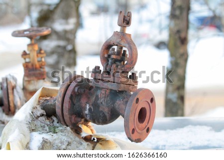 Old, rusty shut-off valve on a heating pipe on a winter background.