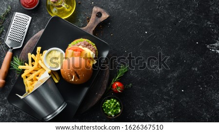 Burger with meat, cheese and french fries. Top view. Free space for your text.