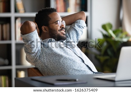 Relaxed calm young african businessman resting looking away sit at desk with laptop hands behind head, satisfied office employee take break feel stress relief peace of mind concept chill at work Royalty-Free Stock Photo #1626375409