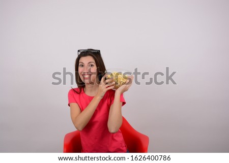smiling woman sitting holding popcorn on an isolated background