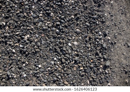 Grey gravel texture. Rustic road surface top view photo. Off-road ride or drive concept. Black gravel stone with sand. Simple and cheap road construction material. Bumpy road surface. Grungy template