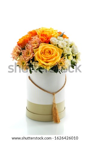 beautiful box of flowers on a white glass table, close-up with a blurred background. floral arrangement in yellow tones as a natural background for the designer. roses, chrysanthemums, greenery