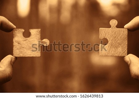 two hands person trying to connect couple Jigsaw wooden puzzle piece with tree  background. one part of whole. symbol of association and connection. success and business solution  strategy