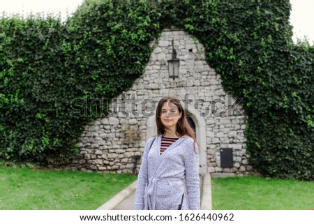 A traveler on the background of an arch with greenery and the entrance to the cave of the Wawel Royal Castle and former barracks. Krakow, Poland. Walls in green. Portrait