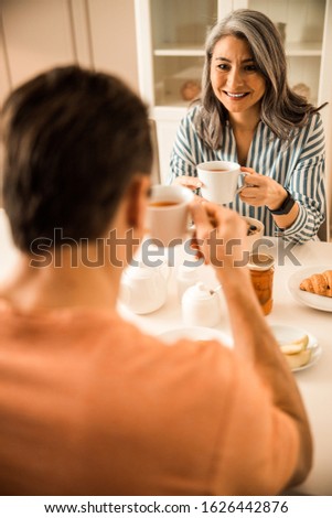 Happy wife holding cup with hot drink while talking with husband stock photo