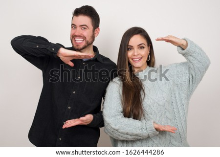 European couple over isolated background gesturing with hands showing big and large size sign, measure symbol. Smiling looking at the camera. Measuring concept.