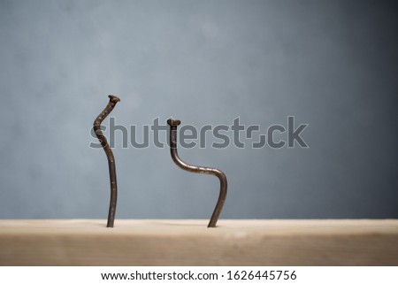 Two bent nails driven into a board. Concept stoop, sciatica and degenerative disc disease - image Royalty-Free Stock Photo #1626445756