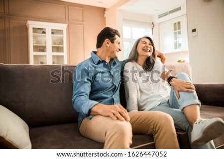 Smiling man hugging beautiful lady while sitting on sofa together stock photo Royalty-Free Stock Photo #1626447052