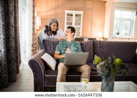 Happy mature couple in love using laptop while sitting on sofa at home stock photo