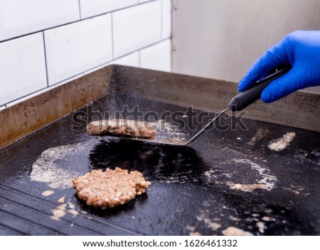 Chef preparing burgers at the kitchen grill stove. Restaurant.