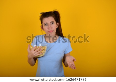 displeased woman with popcorn yellow background