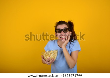 emotional woman with popcorn in her hands watching a 3D movie